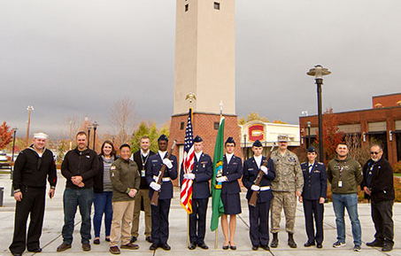 veterans standing in a row in uniform in front of clock tower