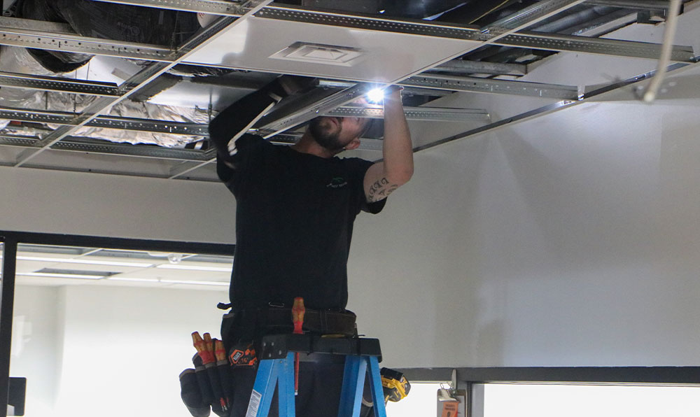 Worker inspects cables in ceiling