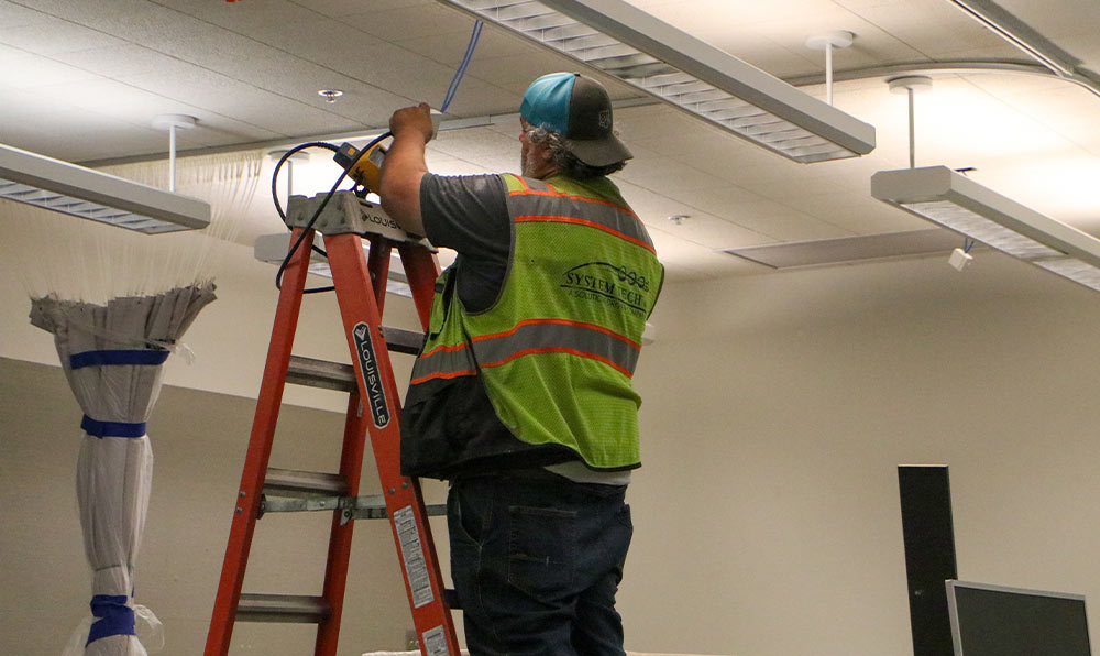 Worker looks at cabling in ceiling