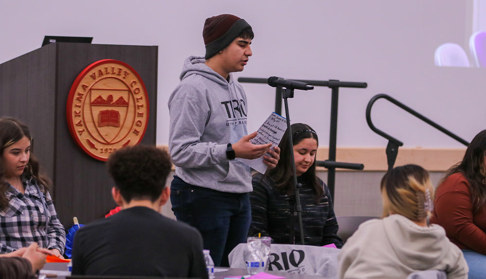 College student reads poem during open mic event.