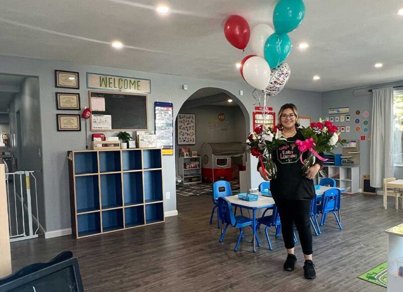 Childcare provider holding balloons in home childcare center.