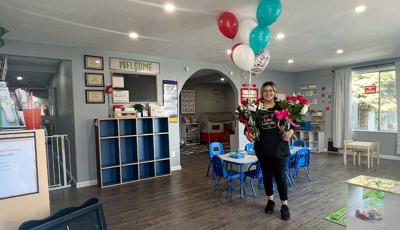 Childcare provider holding balloons in home childcare center.