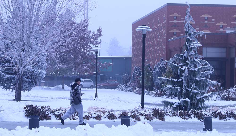 Male student walks across campus in winter