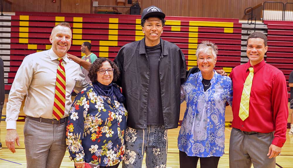 Former basketball player poses with college staff