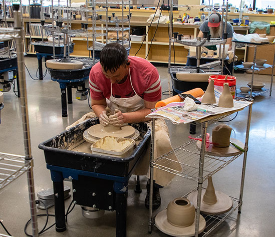 A male student works on a pottery project