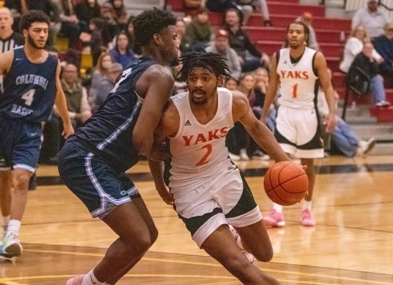 YVC men's basketball player drives around a defender