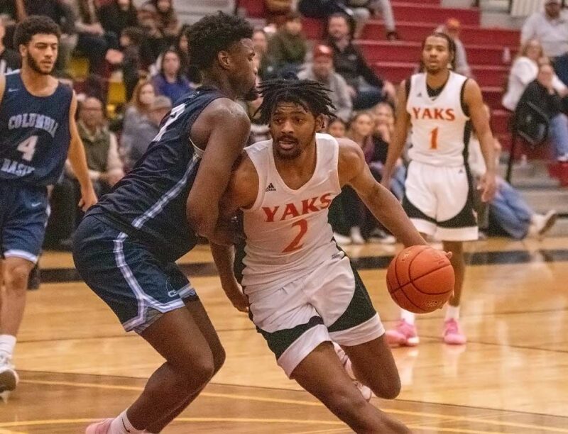 YVC men's basketball player drives around a defender