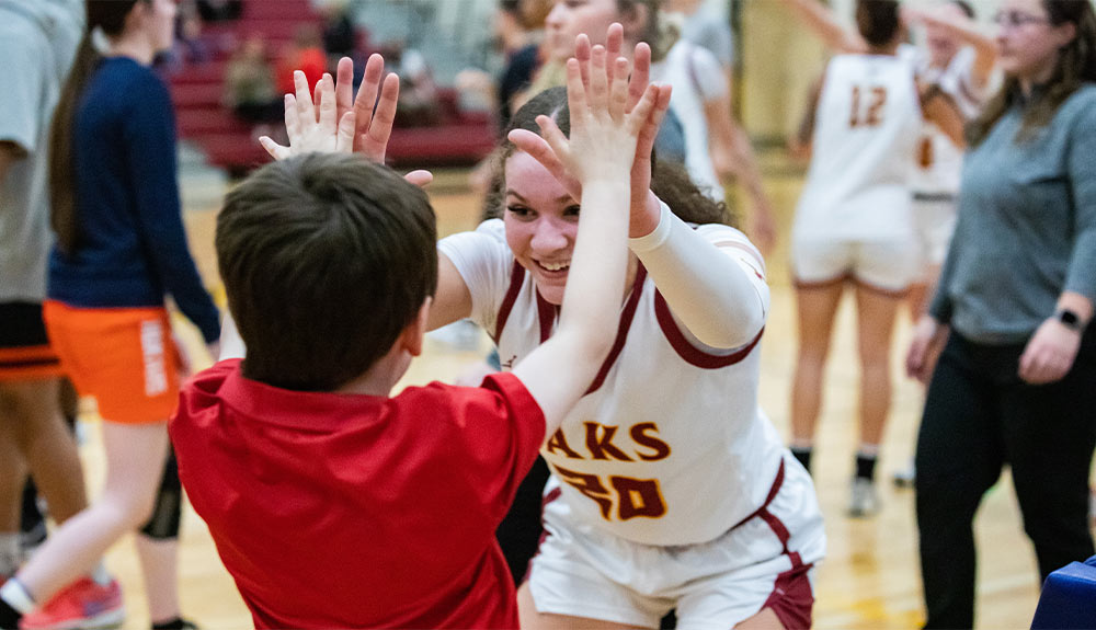 Female basketball player high fives a young fan