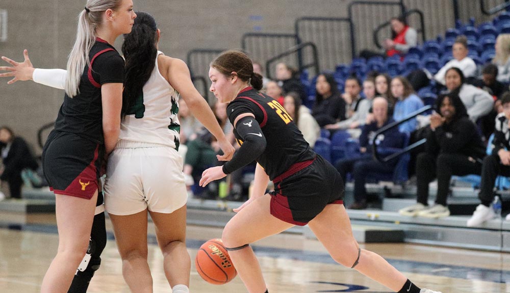 Female basketball player dribbles as teammate sets picks versus defender