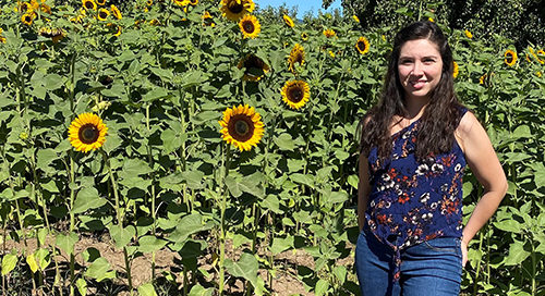 Lizbeth Ochoa standing in front of sunflowers