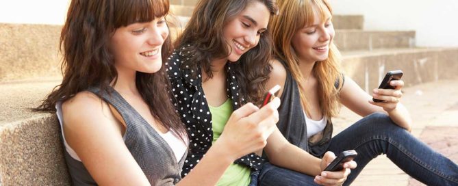 Group of three students looking at cell phones