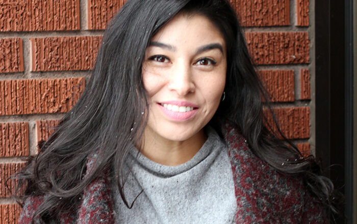 Christina Escobar poses for Student Story picture with a YVC brick building in the background.