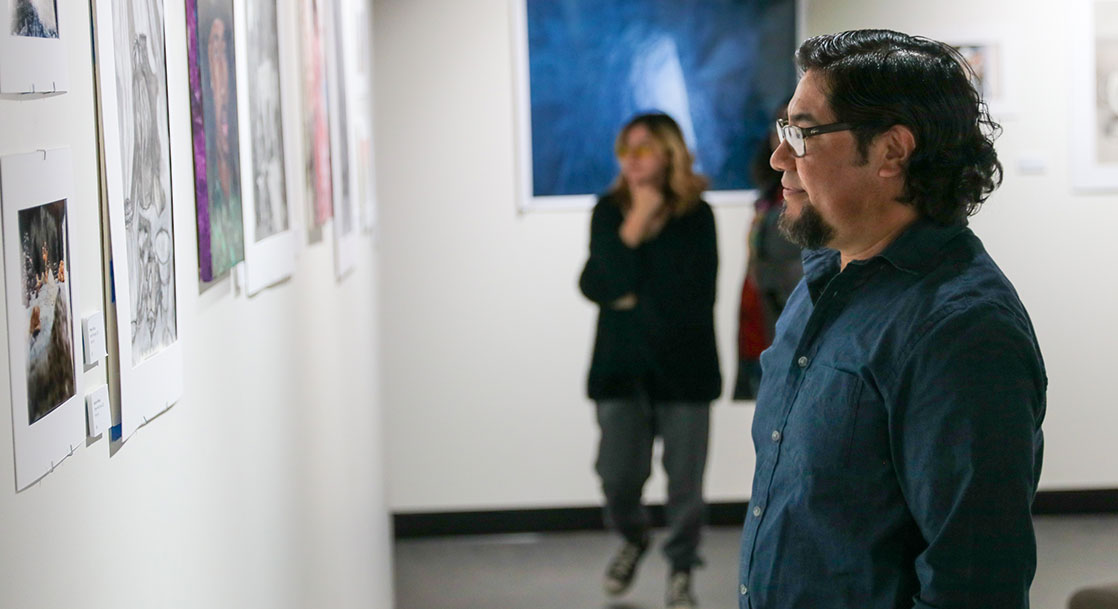 Individuals view the 2023 Department of Visual Arts show in the Larson Gallery